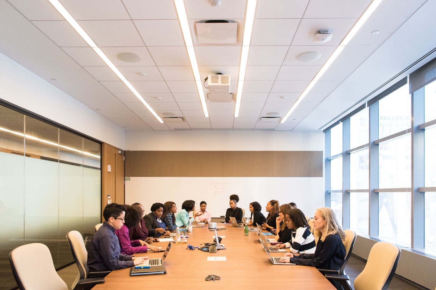 A group of diverse employees are gathered around a bright conference room table.