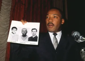 King holds pictures of three young civil rights workers who were murdered.